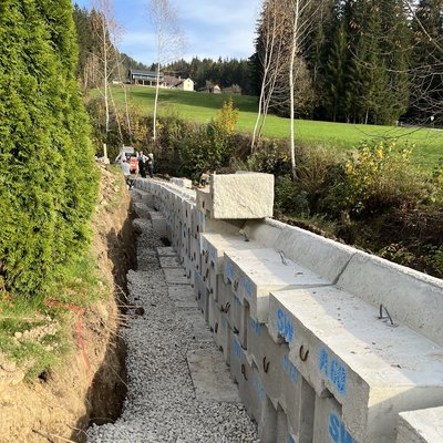 Betonsteine formen stabile Gartenmauer entlang eines leicht geschwungenen Weges