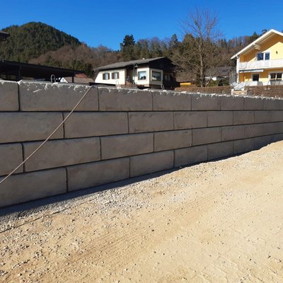 Gerade gesetzte Betonblöcke sichern das Grundstück und schaffen eine ebene Gartenfläche