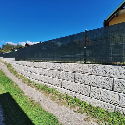 Stützmauer aus Betonblöcken mit Sichtschutzzaun – sichere Lösung zur Abgrenzung eines erhöhten Grundstücks neben einem Gehweg