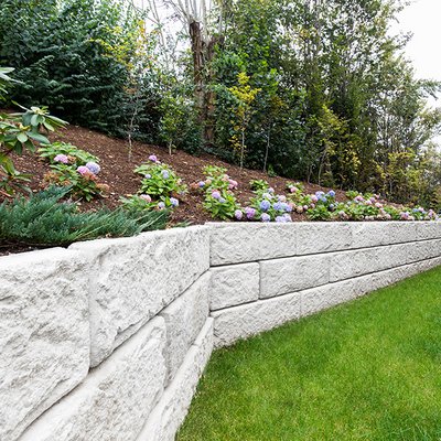 Blumenbeet mit Hang wurde durch stabile Mauer ordentlich abgegrenzt