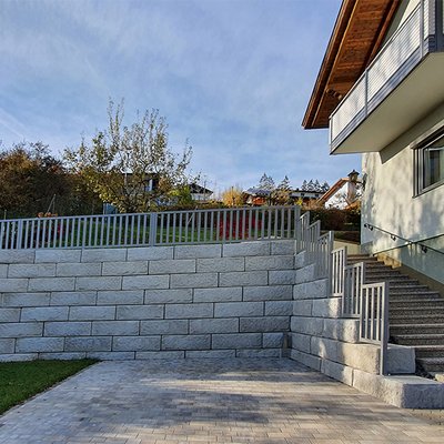 Solide Betonwand mit Zaun und Stufen schafft sicheren Zugang zum Garten auf zwei Ebenen