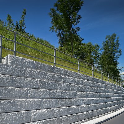 Stabile Mauer mit Metallzaun ermöglicht sichere Straßenführung am Hangverlauf