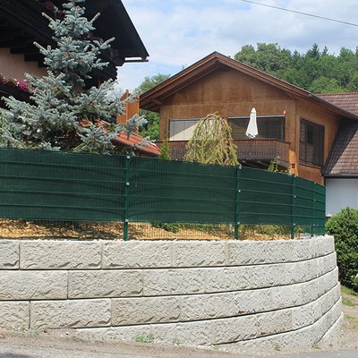 Hang mit runder Betonwand abgefangen – grüner Sichtschutz sorgt für Privatsphäre