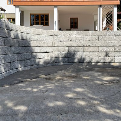 Terrassenfläche mit gebogener Stützmauer aus Betonsteinen auf Hanggrundstück erweitert