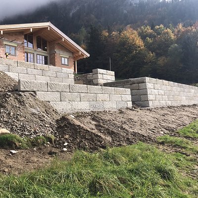 Terrassenförmige Stützwand aus Beton sichert das Hanggrundstück direkt am Haus – stabil und natürlich
