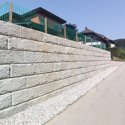 Helle Betonmauer sichert das Hanggrundstück und schafft klare Abgrenzung zur Straße