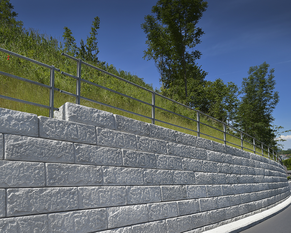 Solide Stützwand aus Betonsteinen mit integriertem Geländer – ideal bei Böschungen neben Gehwegen